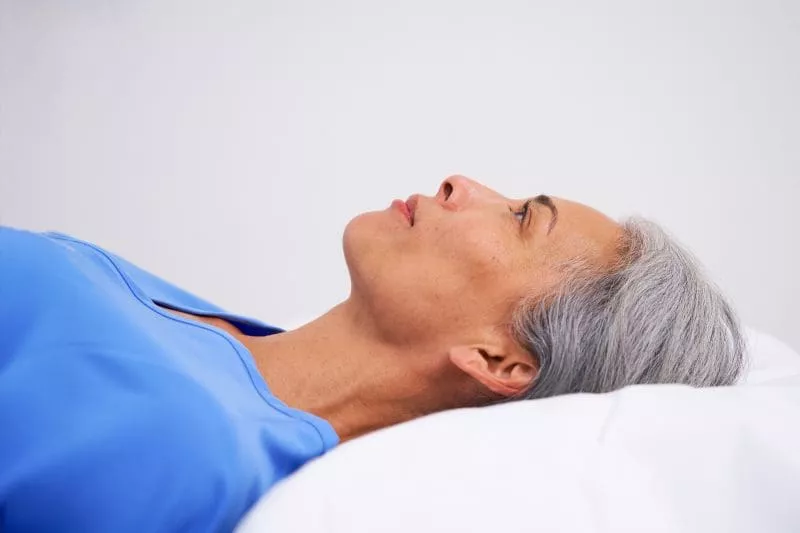 Close-up side profile of a patient lying on a medical imaging table with head supported by a pillow.