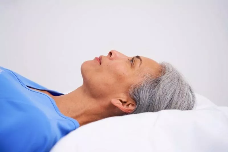 Close-up side profile of a patient lying on a medical imaging table with head supported by a pillow.