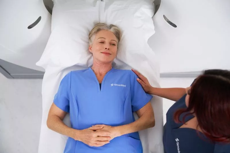 Patient lying calmly on an MRI table while a radiographer offers reassurance.