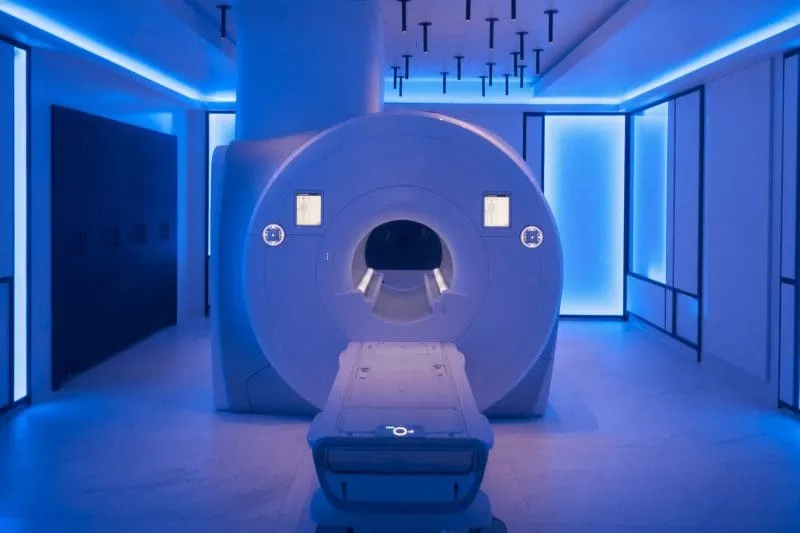 Empty MRI scanner in a modern imaging room with blue ambient lighting.