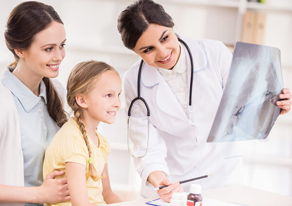 A pediatric doctor helping a young girl and her mom.